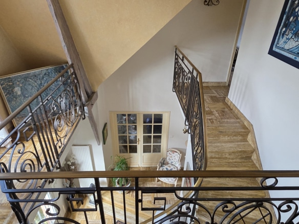 Interior view of a house with a cathedral staircase and a wrought iron balcony.