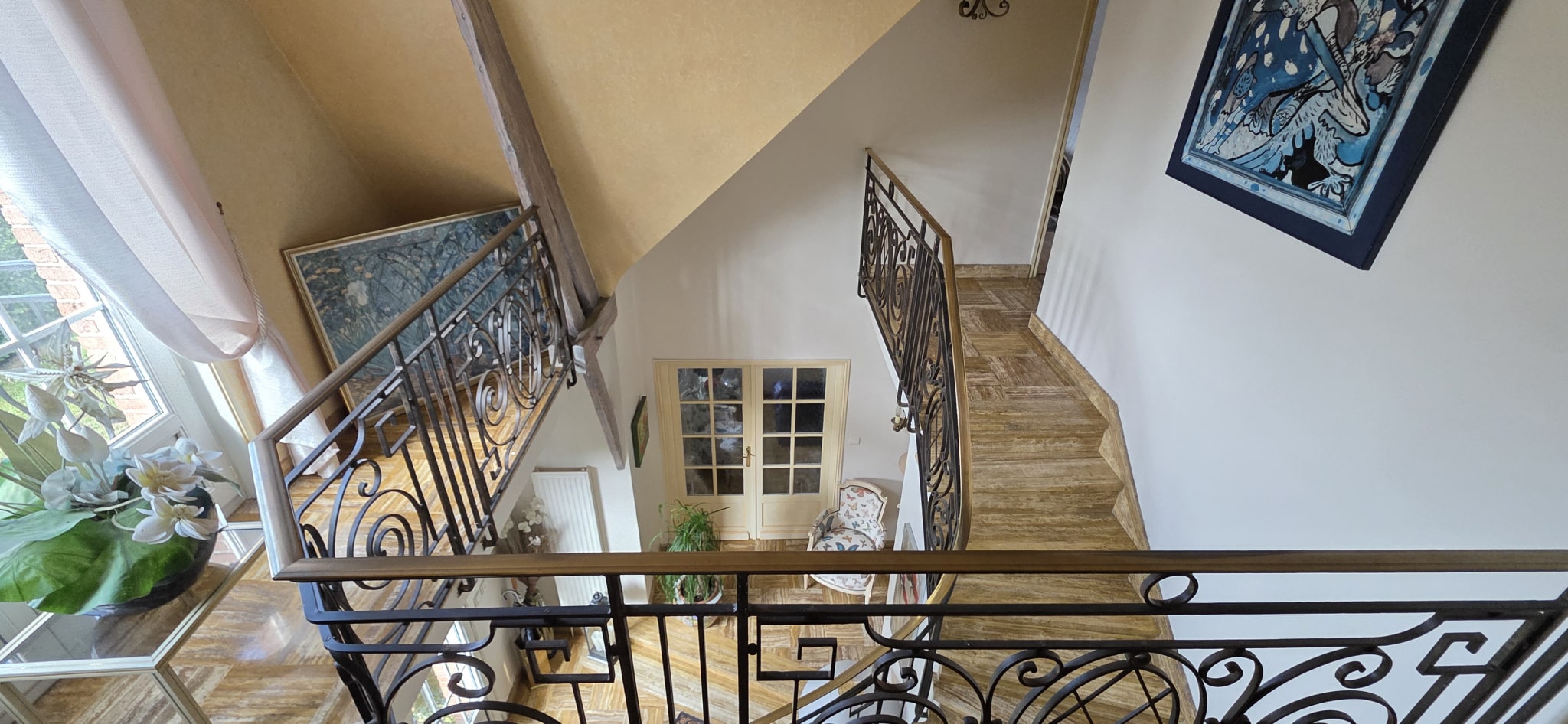Interior of a characterful house Interior view of a house with a cathedral staircase and a wrought iron balcony.