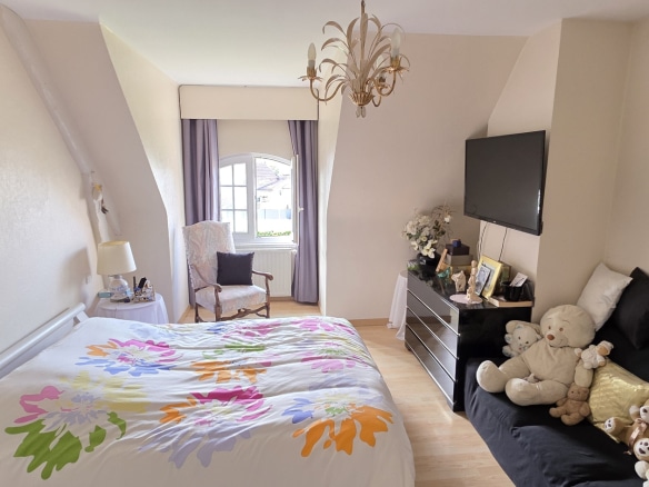 Bedroom in a townhouse in Bauvin, with bed and sofa, decorated with stuffed animals.