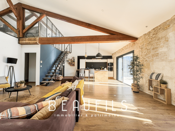 Spacious 191m2 loft with open living room and kitchen, stone walls, and exposed beams.
