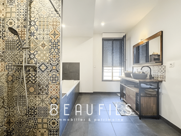 Bathroom with decorative tiles, bathtub and wooden furniture.