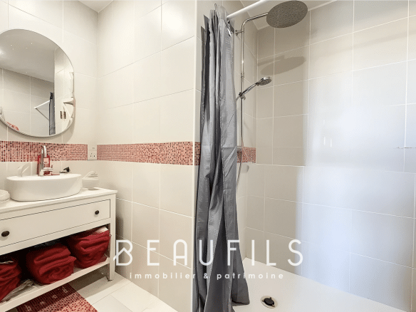 Modern bathroom with shower and sink, walls tiled in white and red.