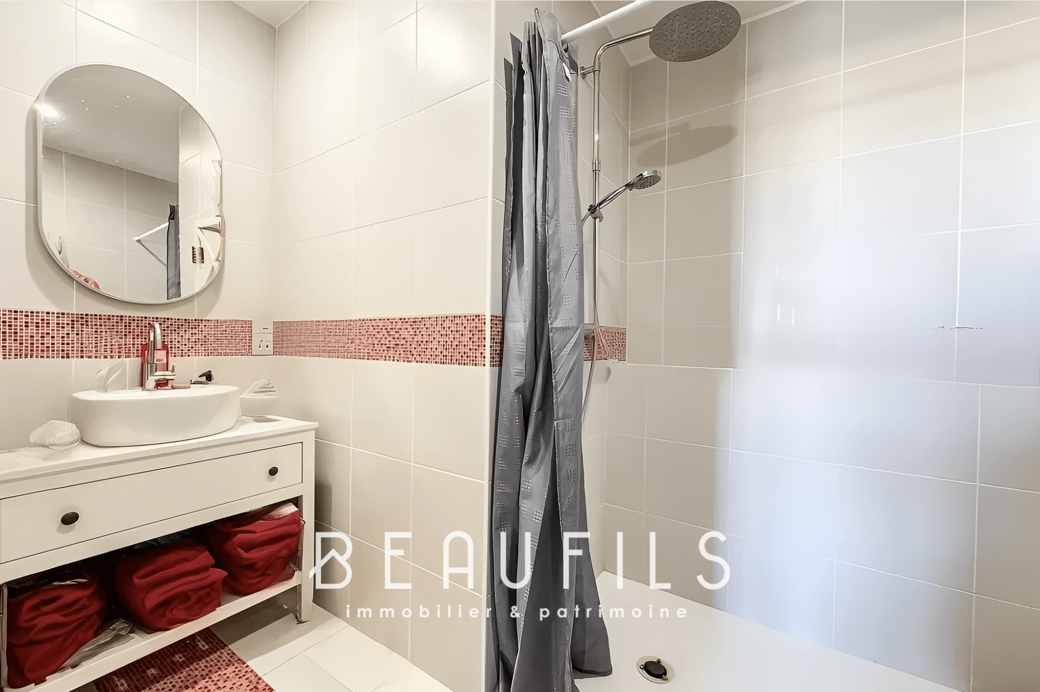 Modern bathroom with shower and sink, walls tiled in white and red.