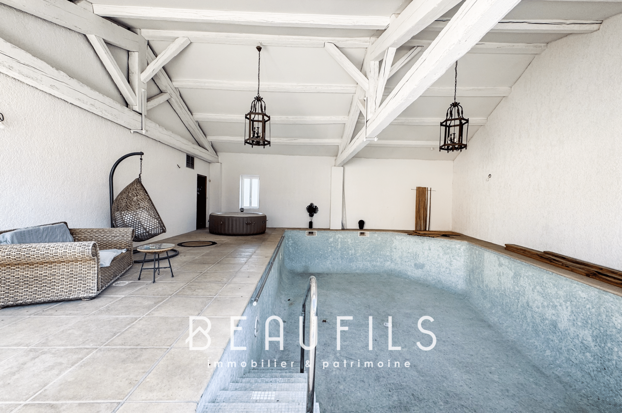 Interior of a loft with a swimming pool to be renovated, white walls and exposed beams.