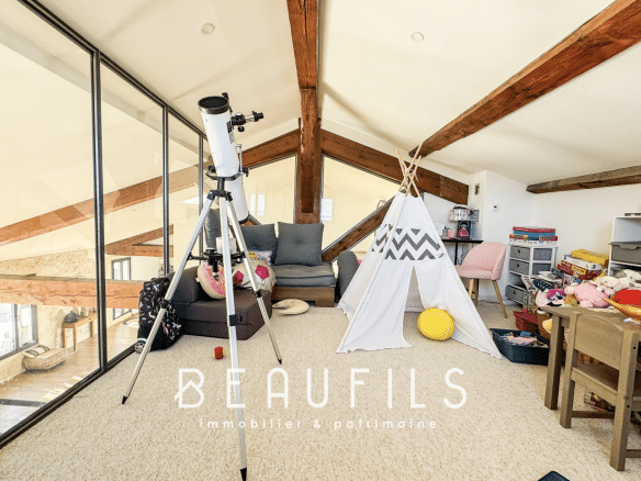 Interior of a loft with exposed beams, a telescope and a children's play area.