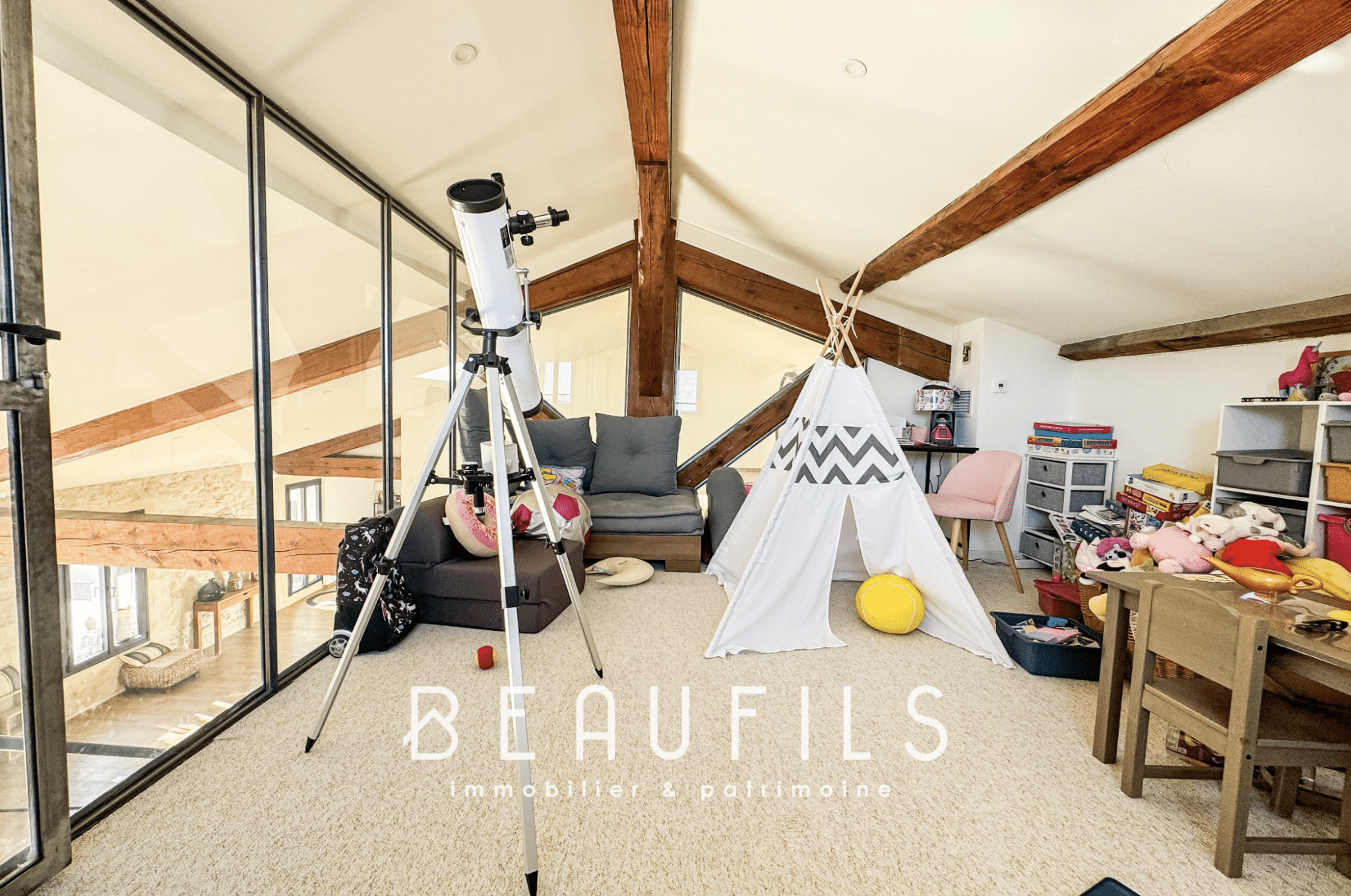 Interior of a loft with exposed beams, a telescope and a children's play area.
