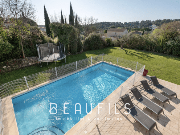 View of the swimming pool and garden of an architect-designed villa in Nîmes, with sun loungers and trampoline.