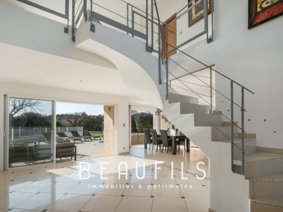 Interior of a modern architect-designed villa with staircase and large open-plan living area opening onto the outside.