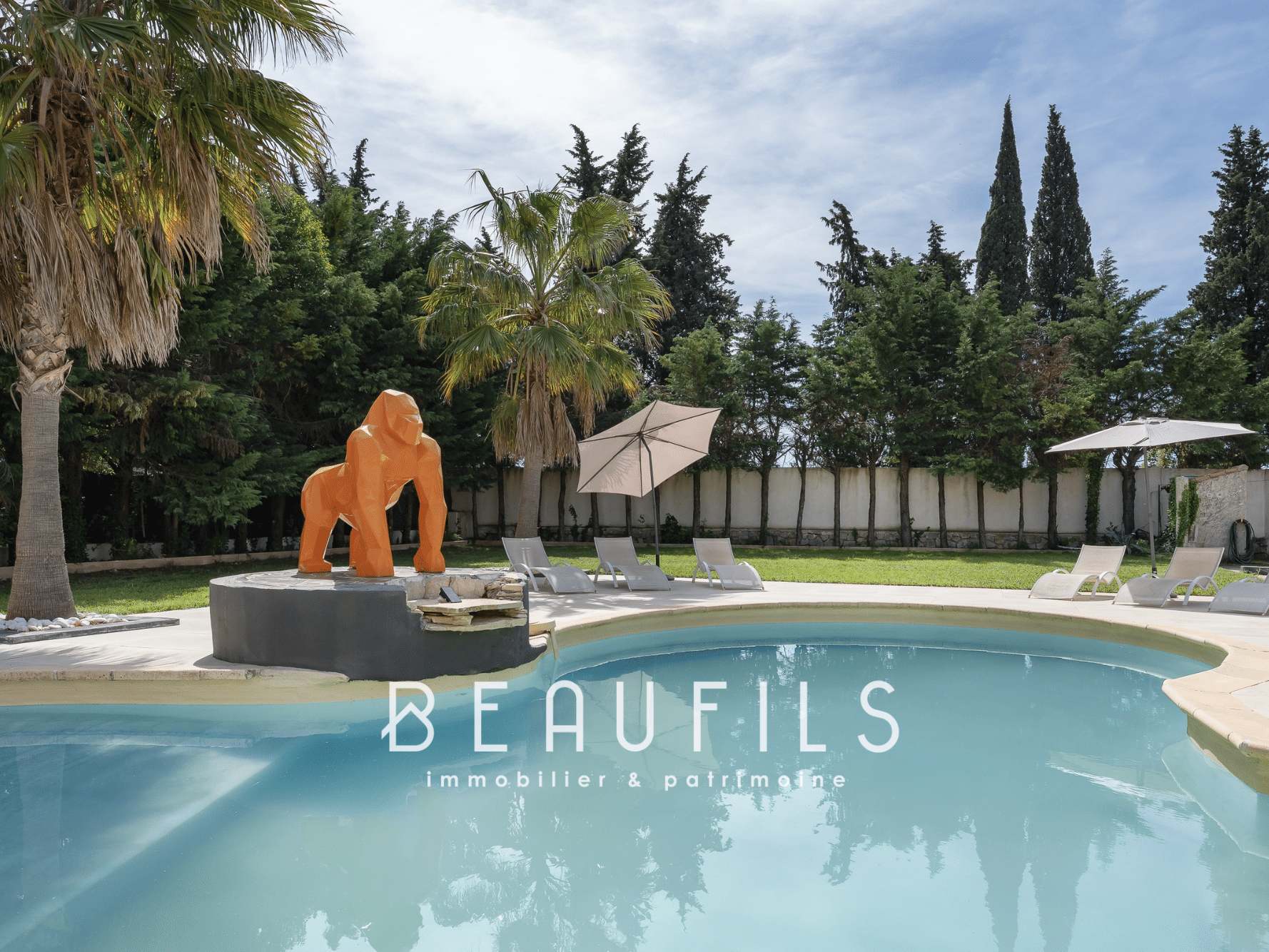 Swimming pool with outdoor gorilla sculpture, surrounded by palm trees and green space.