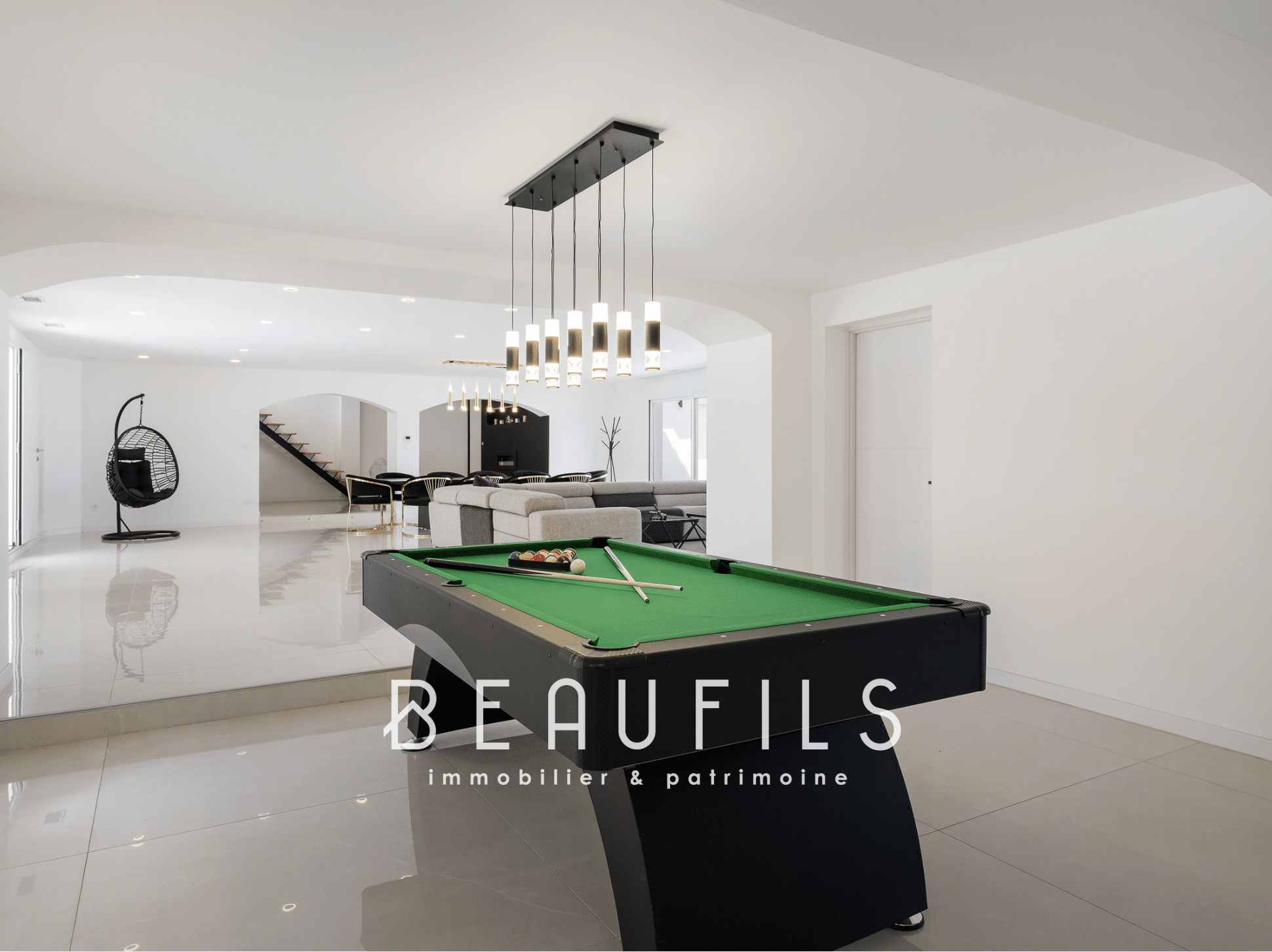 Interior of a neo-Provençal farmhouse with a billiard table in a large, bright living room.
