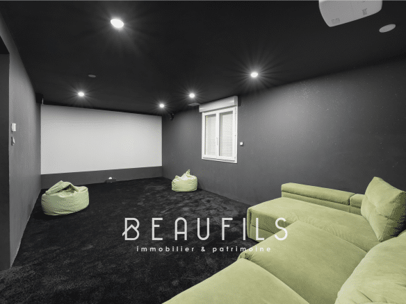 Interior of a leisure space with a green sofa and poufs, dark walls and modern lighting.