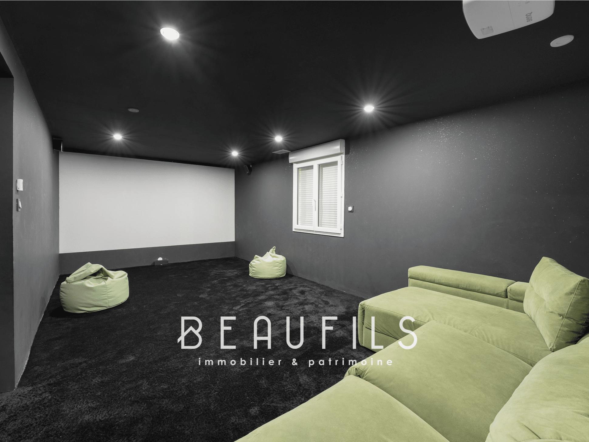 Interior of a leisure space with a green sofa and poufs, dark walls and modern lighting.