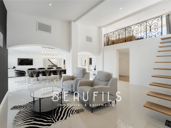 Interior of a renovated neo-Provençal farmhouse with a modern living room and wooden staircase.