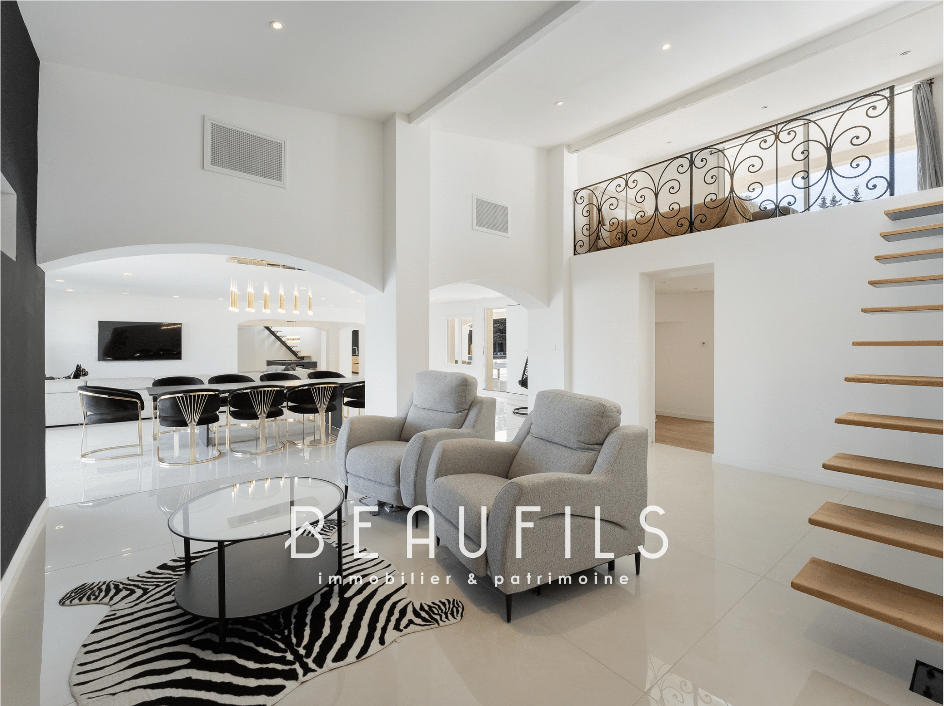 Interior of a renovated neo-Provençal farmhouse with a modern living room and wooden staircase.