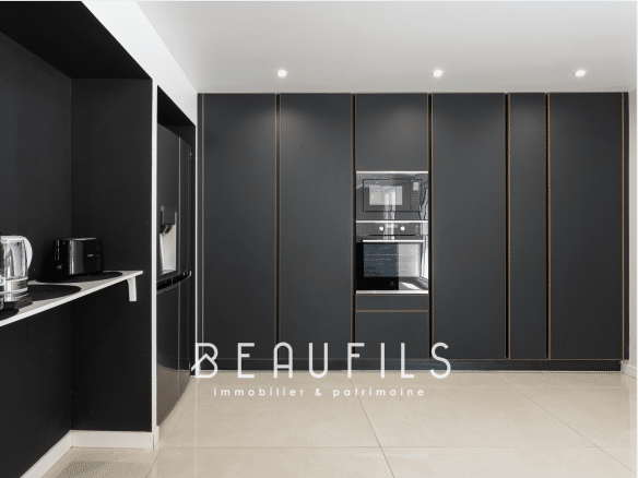 Modern kitchen with black furniture and integrated appliances in a neo-Provençal farmhouse.