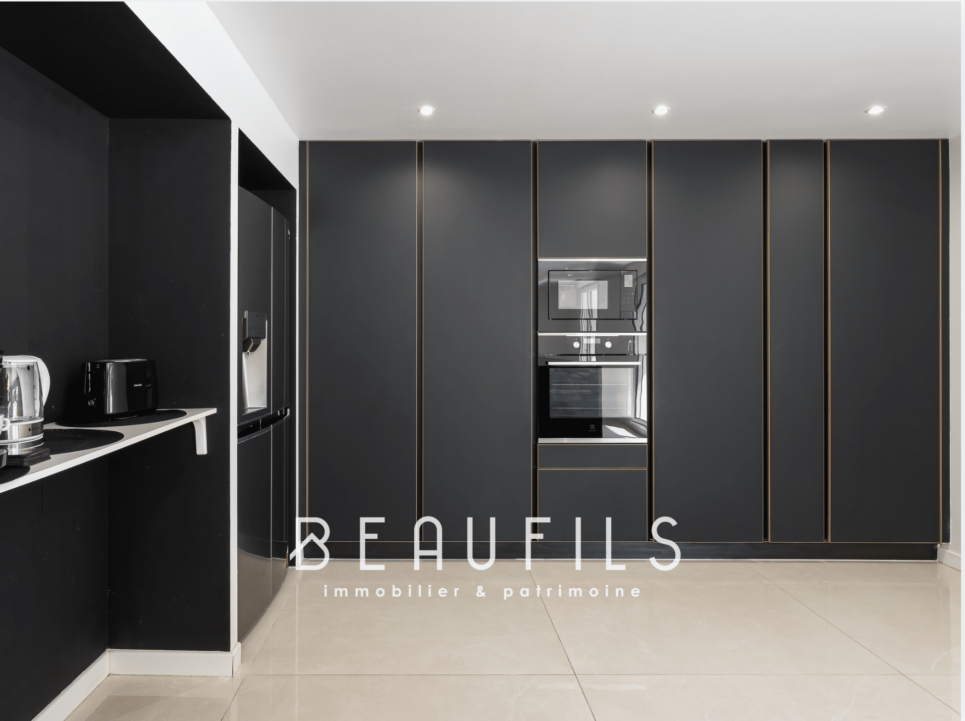 Modern kitchen with black furniture and integrated appliances in a neo-Provençal farmhouse.
