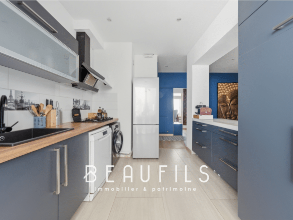 Modern kitchen in a renovated apartment with grey furniture and a wooden worktop.