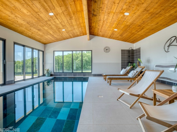 Interior of a renovated stone property with swimming pool and sun loungers, overlooking the countryside.