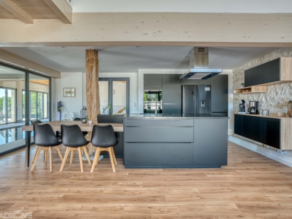Modern open-plan kitchen with dining table and views of the outside in a renovated stone property.