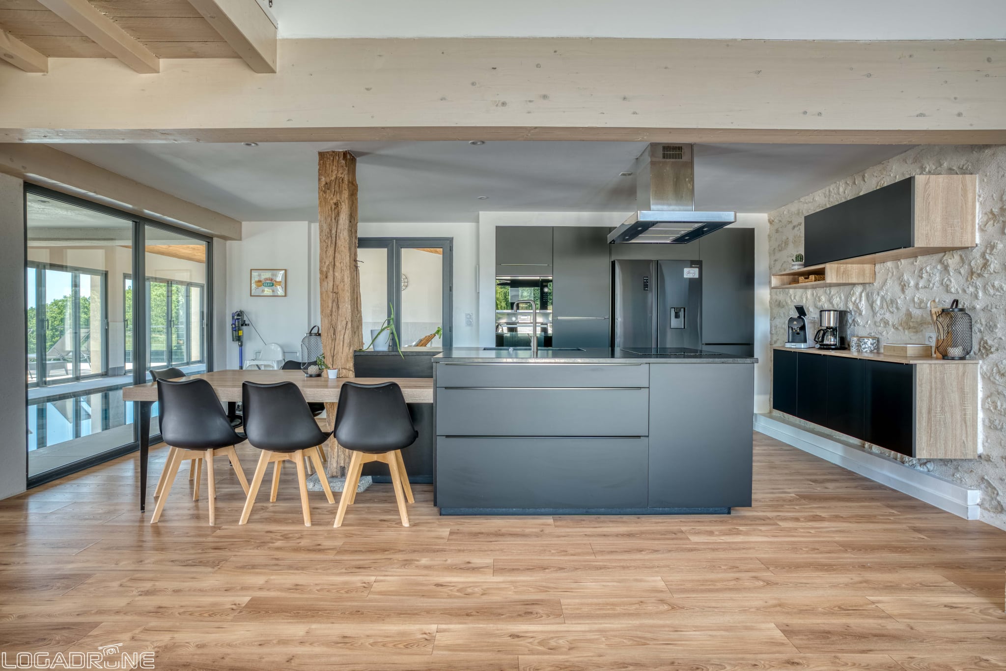 Modern open-plan kitchen with dining table and views of the outside in a renovated stone property.