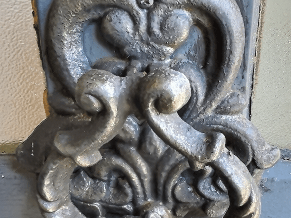 Poignée de porte en métal ornée, style XVIIIe siècle, sur un fond de bois.