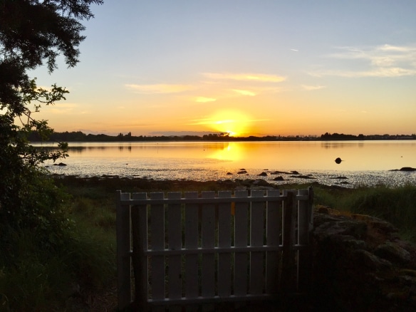 Coucher de soleil sur un plan d'eau avec une clôture en bois au premier plan, près de Pont-l'Abbé.