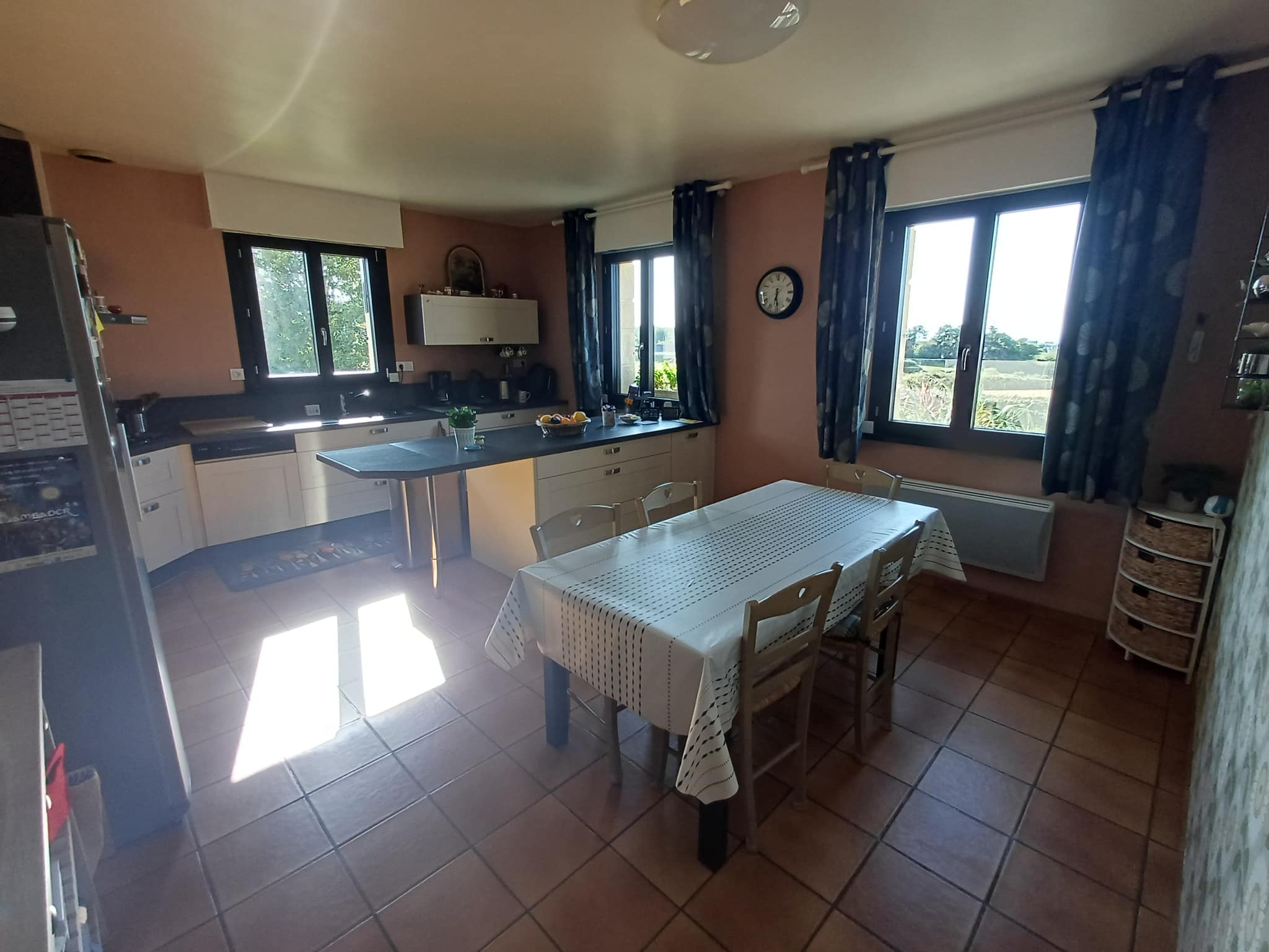 Spacious kitchen with dining table and windows overlooking the outside.