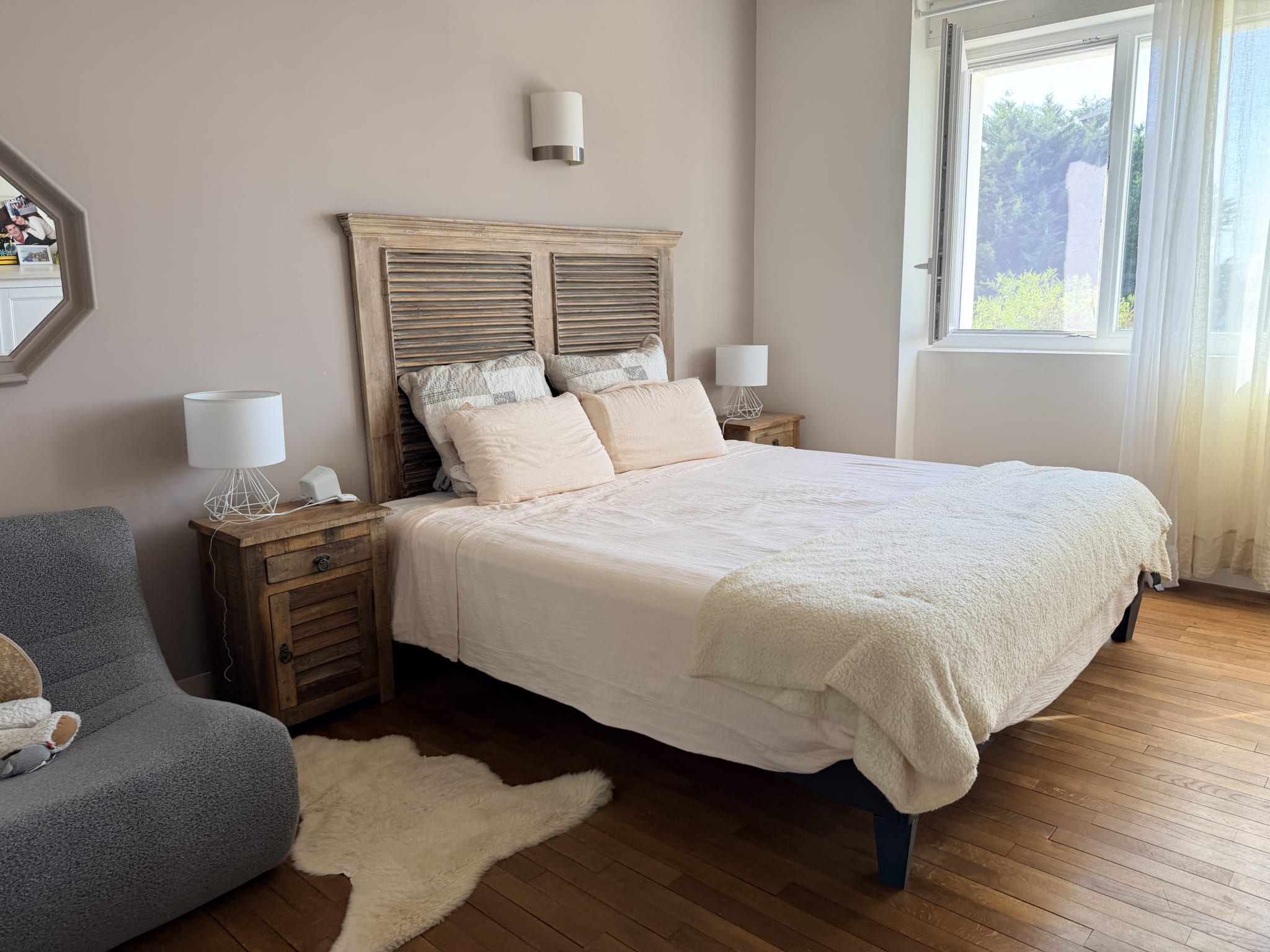 Chambre lumineuse avec lit double, lampes de chevet et fenêtre ouverte.
