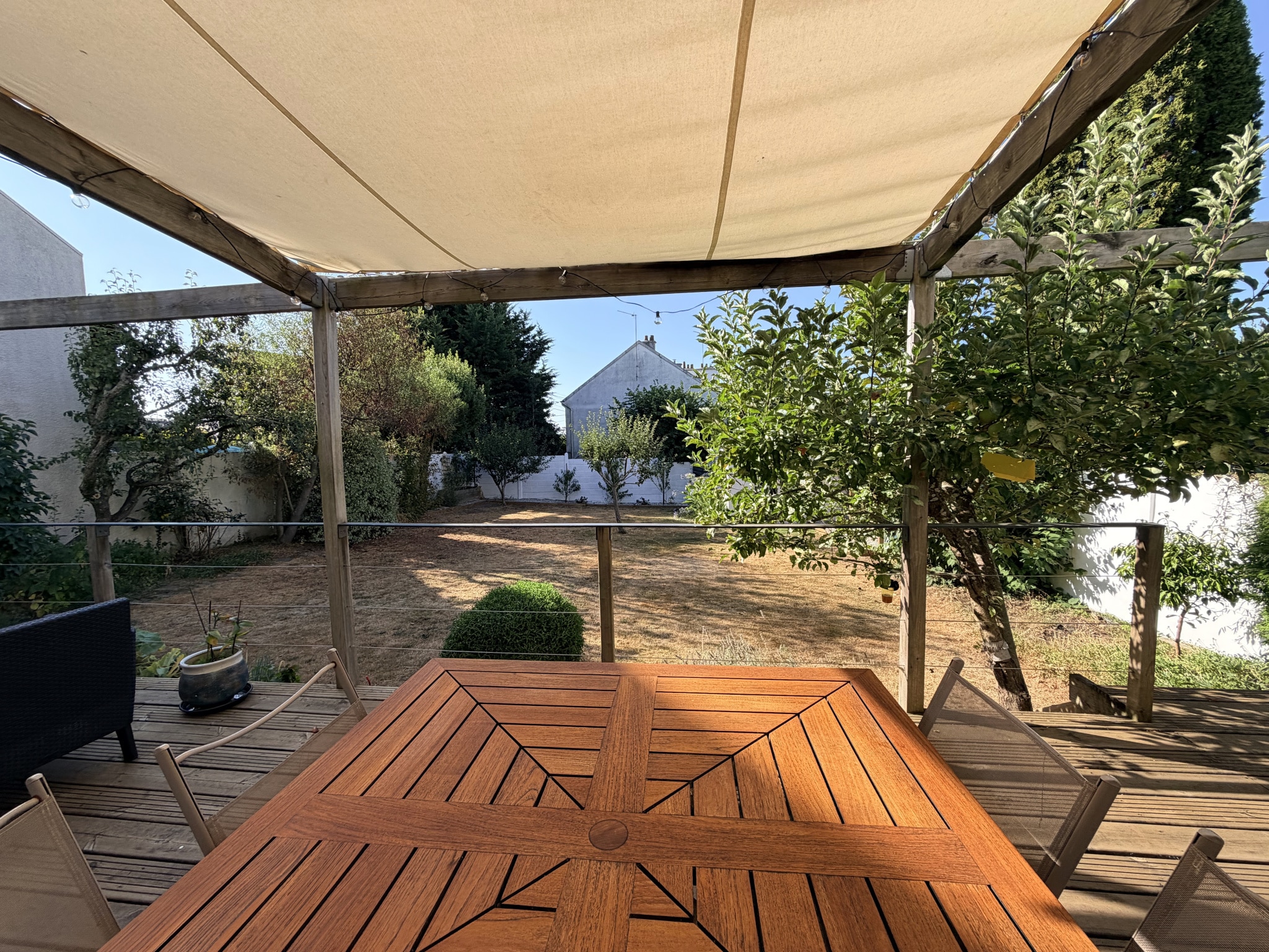 Terrasse en bois avec table, vue sur jardin à Auray.