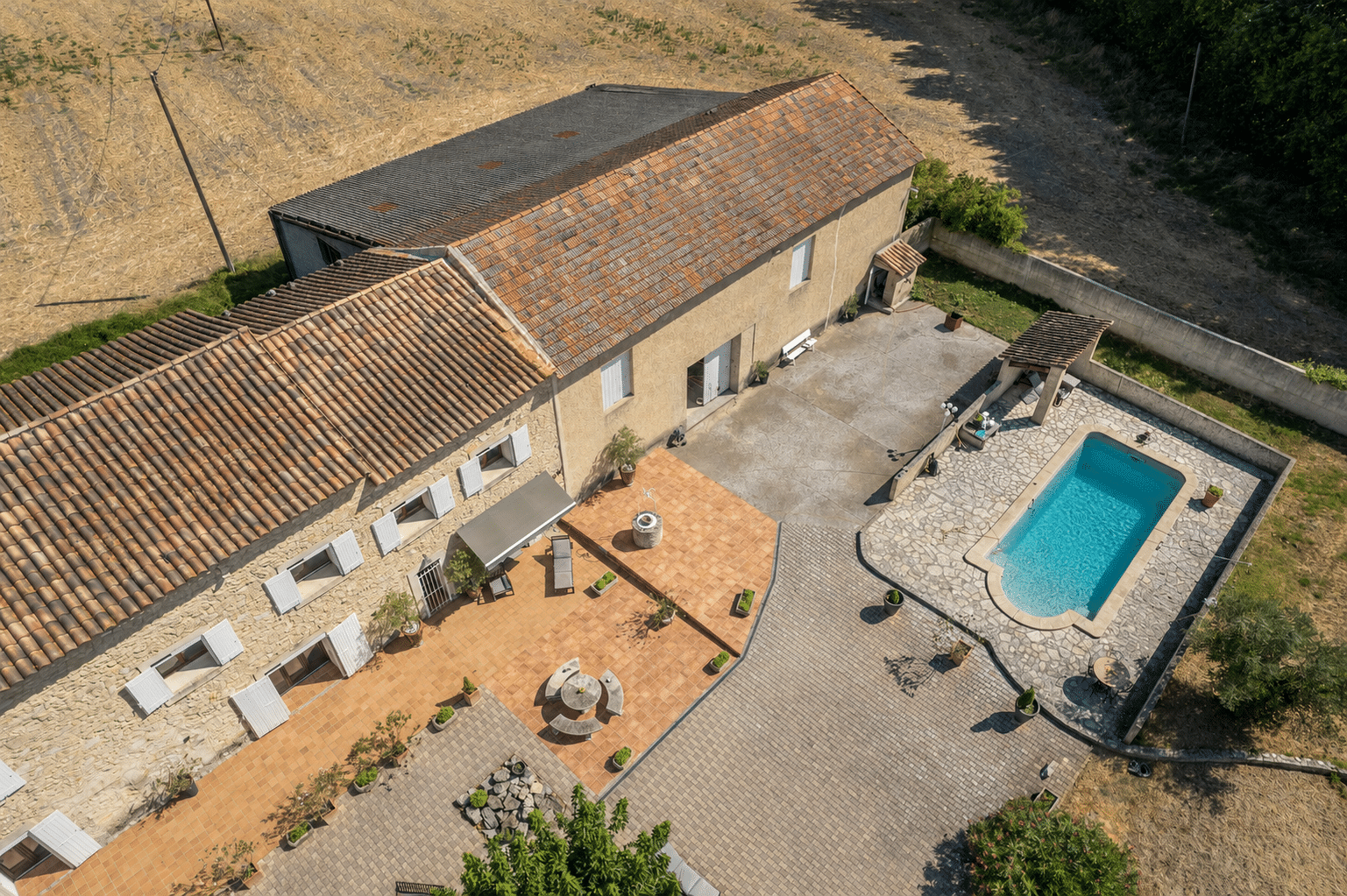 Vue aérienne d'un mas en pierre avec piscine et terrasse, situé en campagne près de L'Isle-sur-la-Sorgue.