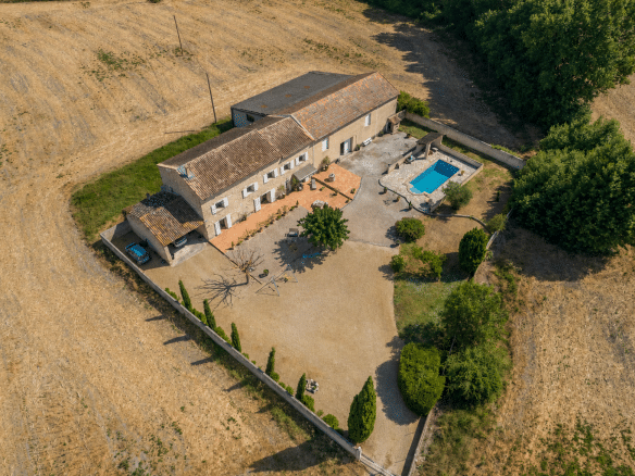 Vue aérienne d'un mas en pierre avec piscine et jardin, entouré de champs à L'Isle-sur-la-Sorgue.