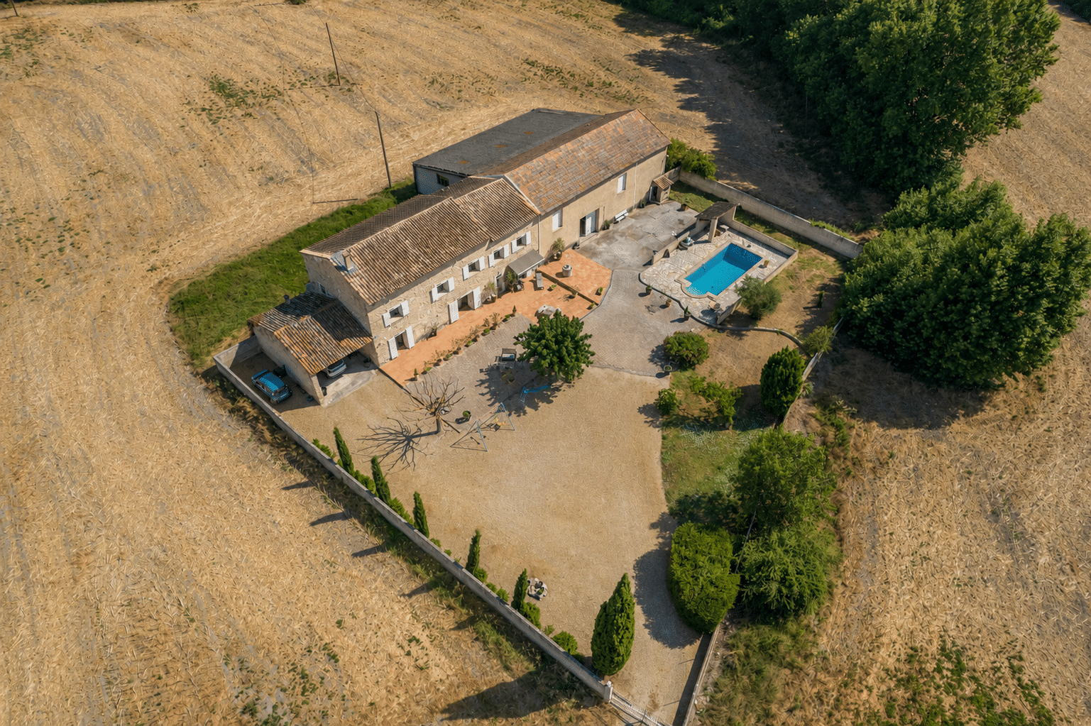 Vue aérienne d'un mas en pierre avec piscine et jardin, entouré de champs à L'Isle-sur-la-Sorgue.