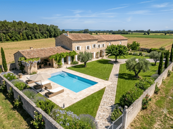 Vue aérienne d'un mas en pierre avec piscine et jardin, entouré de champs à L'Isle-sur-la-Sorgue.