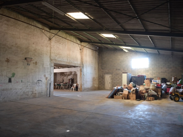 Intérieur d'un grand espace de stockage avec des cartons et des objets divers.