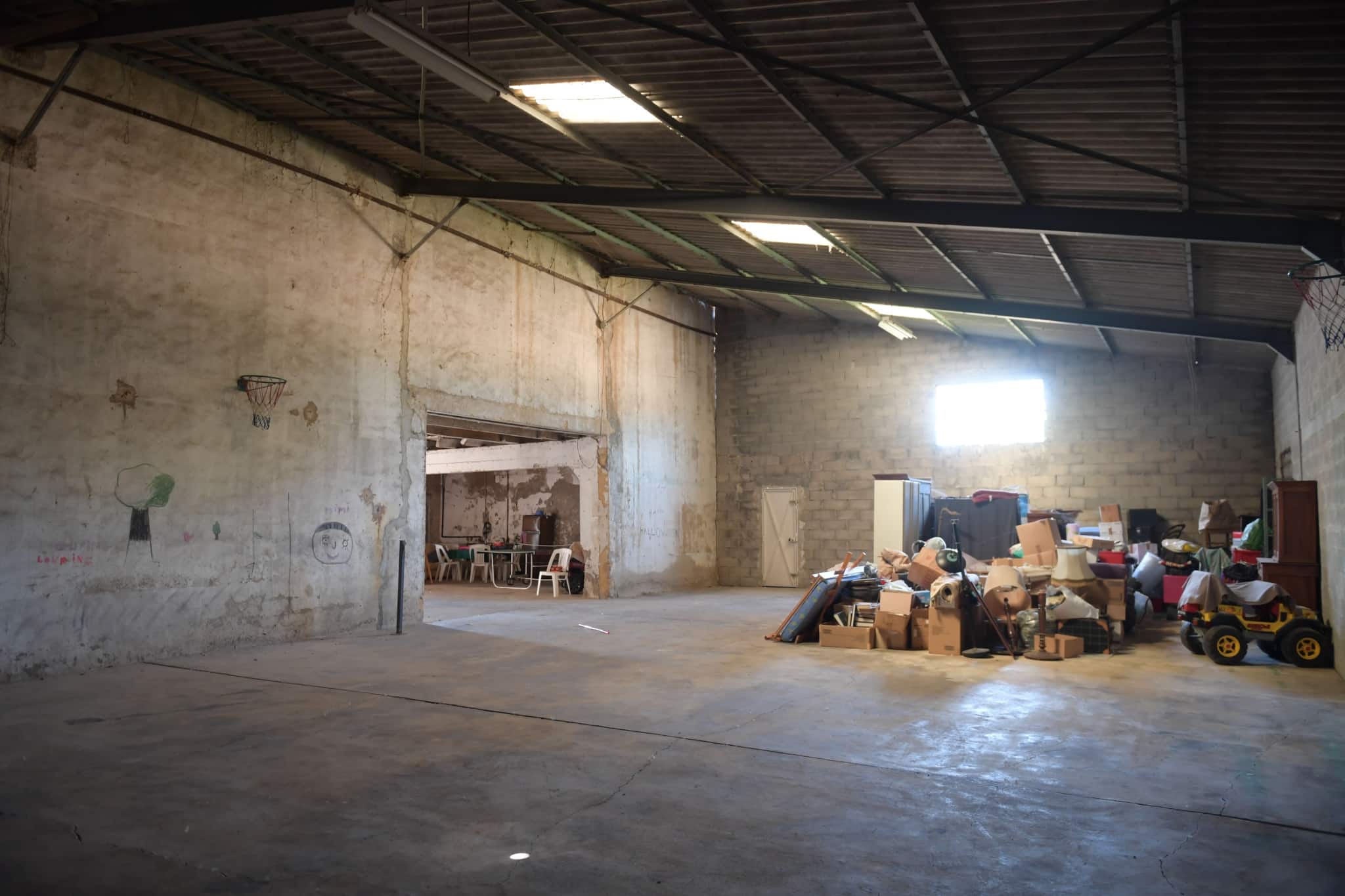 Intérieur d'un grand espace de stockage avec des cartons et des objets divers.