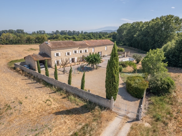 Vue aérienne d'un mas en pierre entouré de champs et d'arbres, situé près de L'Isle-sur-la-Sorgue.