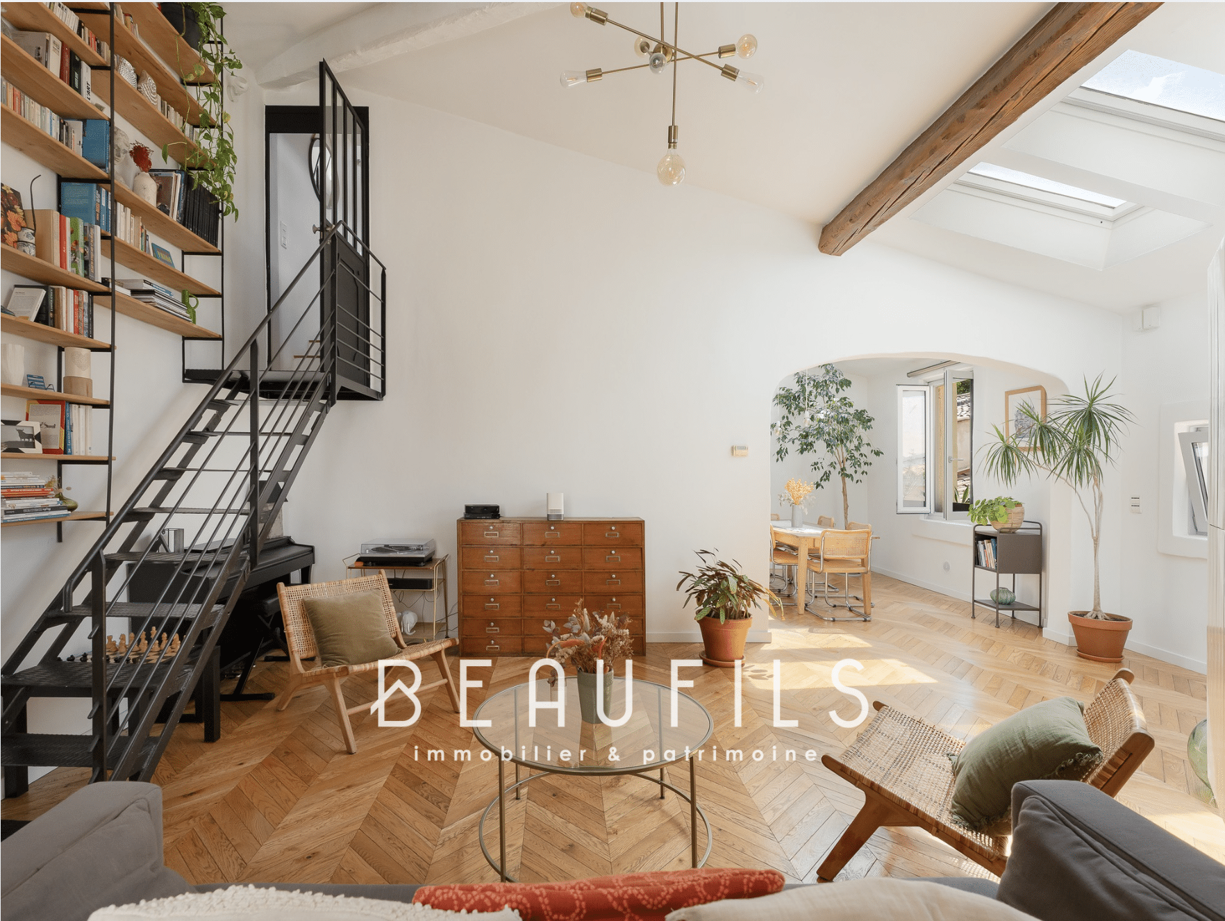Intérieur d'une maison rénovée à Montpellier avec un escalier métallique, un salon lumineux et un parquet en bois.