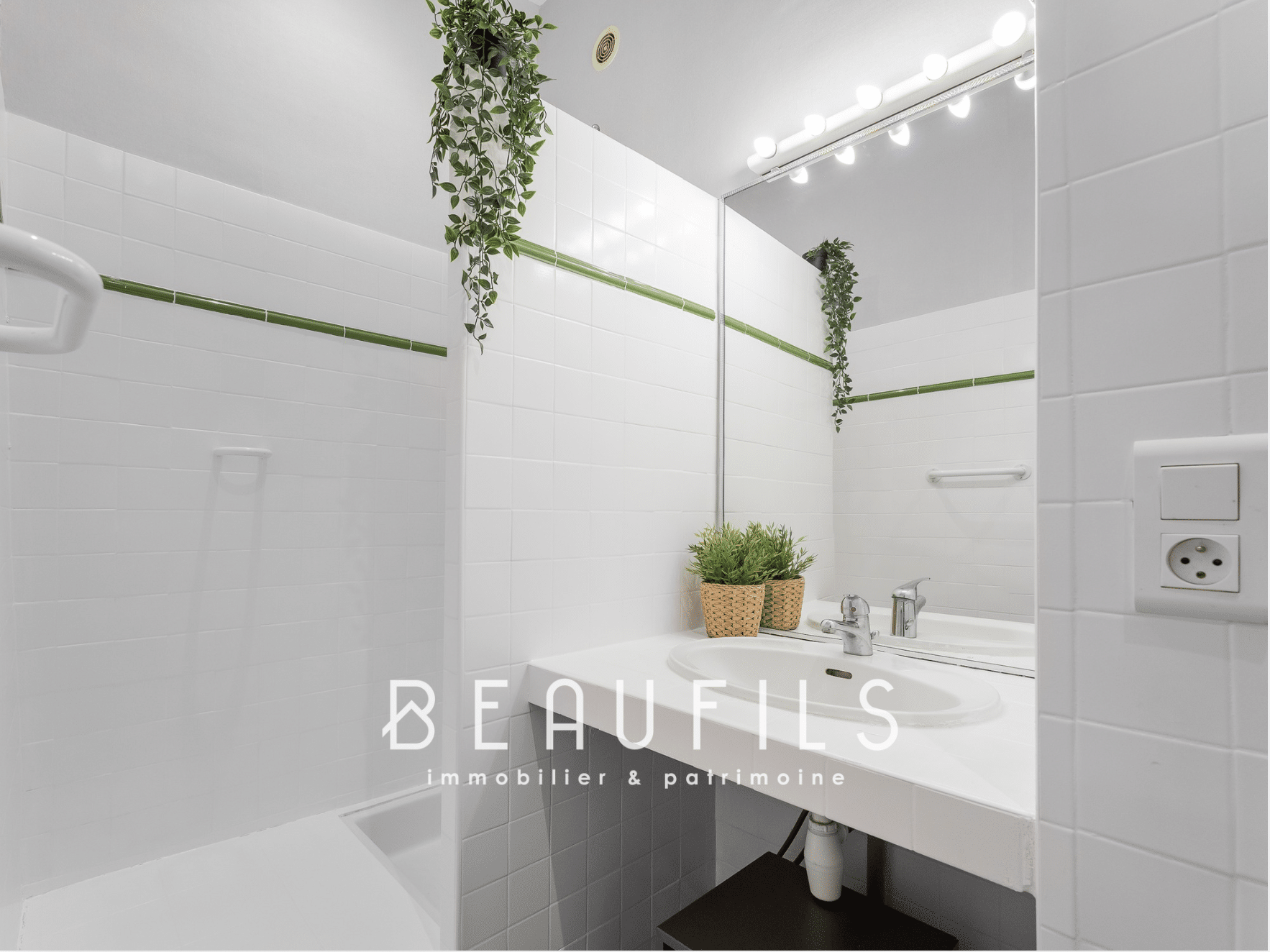 Salle de bain moderne avec carrelage blanc et miroir lumineux.