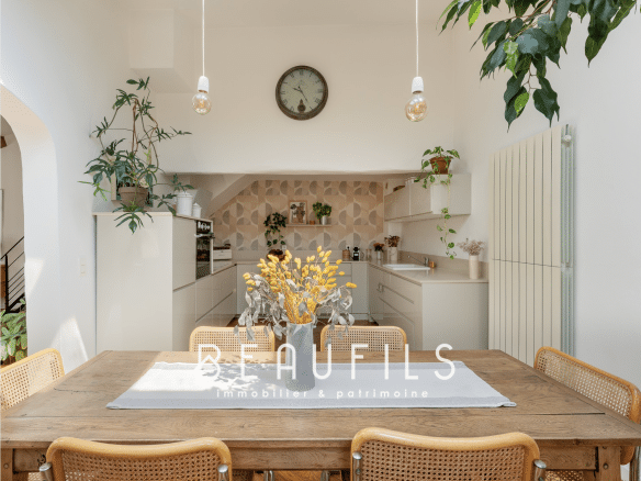 Intérieur d'une maison rénovée à Montpellier avec une grande table en bois et une cuisine moderne.
