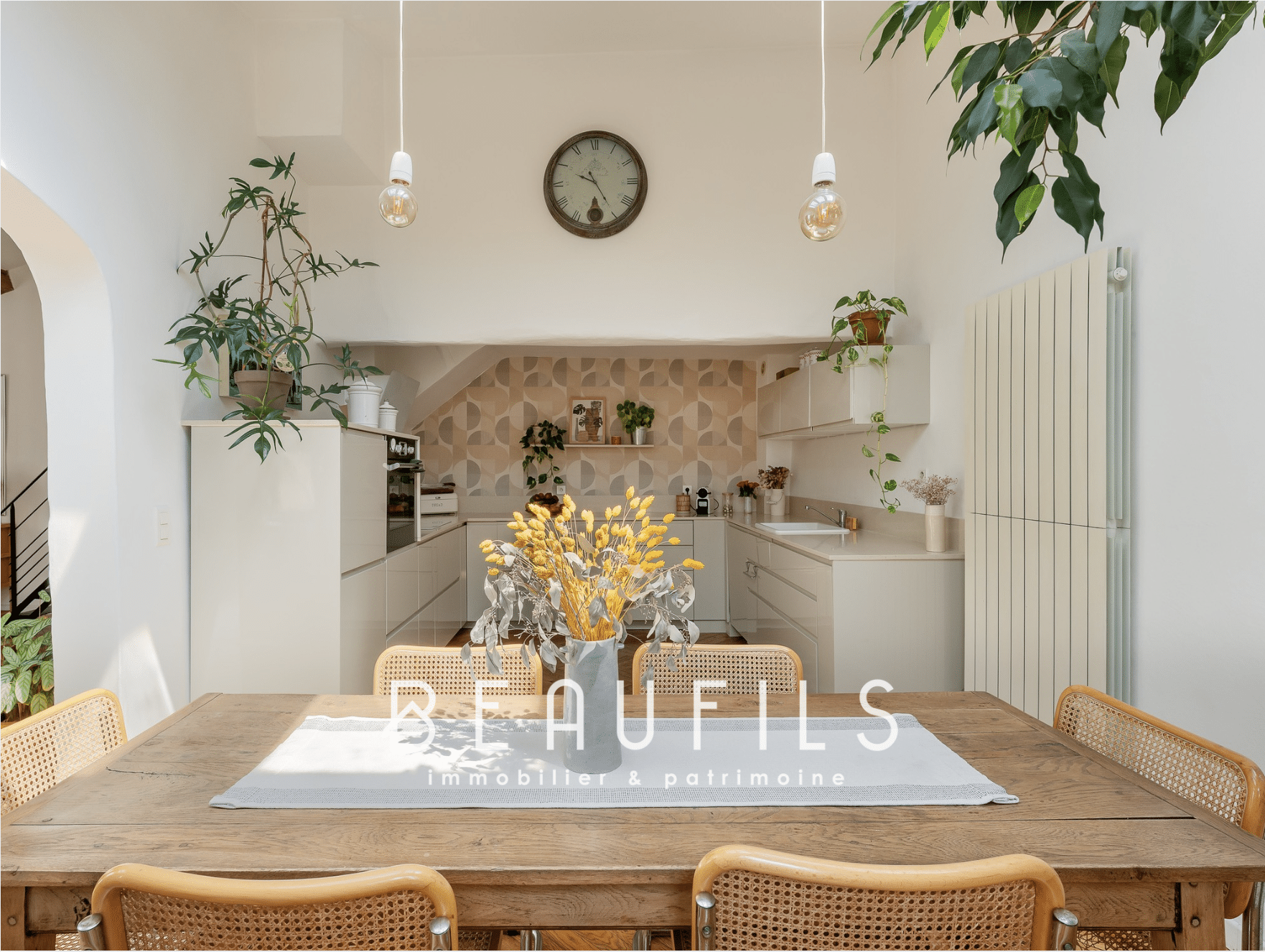 Intérieur d'une maison rénovée à Montpellier avec une grande table en bois et une cuisine moderne.