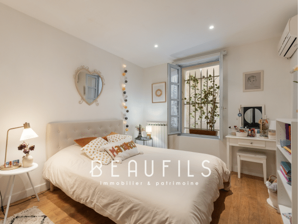 Chambre d'une maison rénovée à Montpellier avec lit, bureau et fenêtre donnant sur l'extérieur.