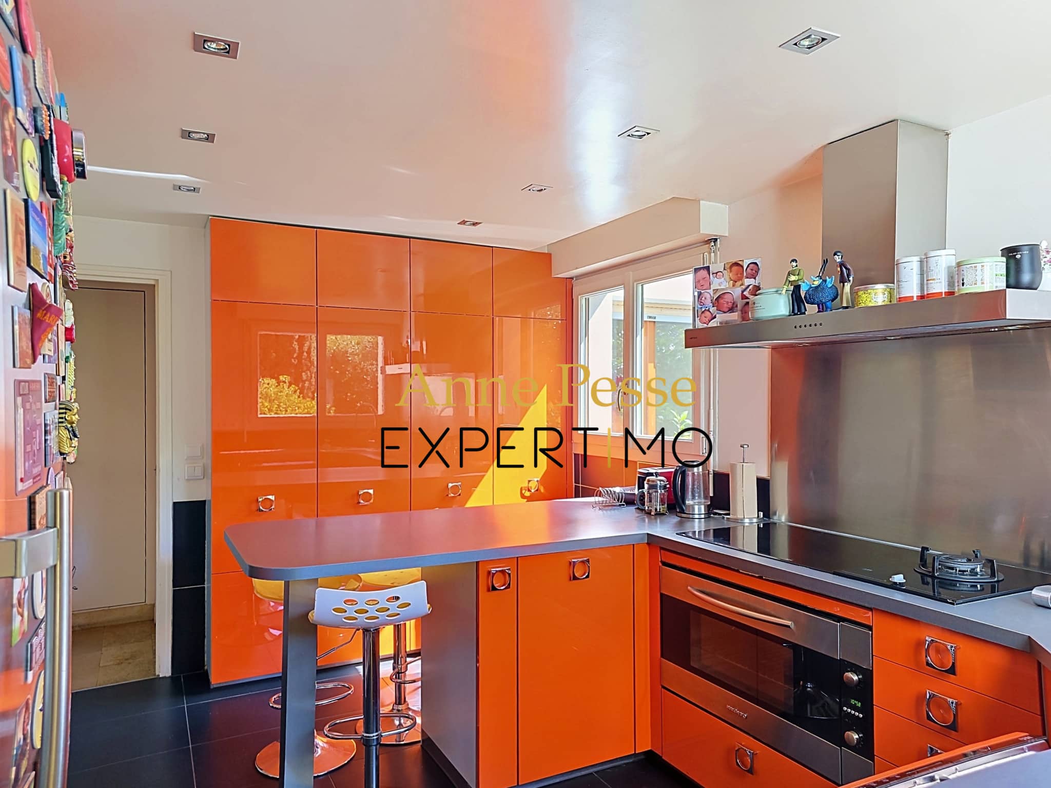 Modern kitchen with orange furniture and a stainless steel worktop in an architect-designed villa.