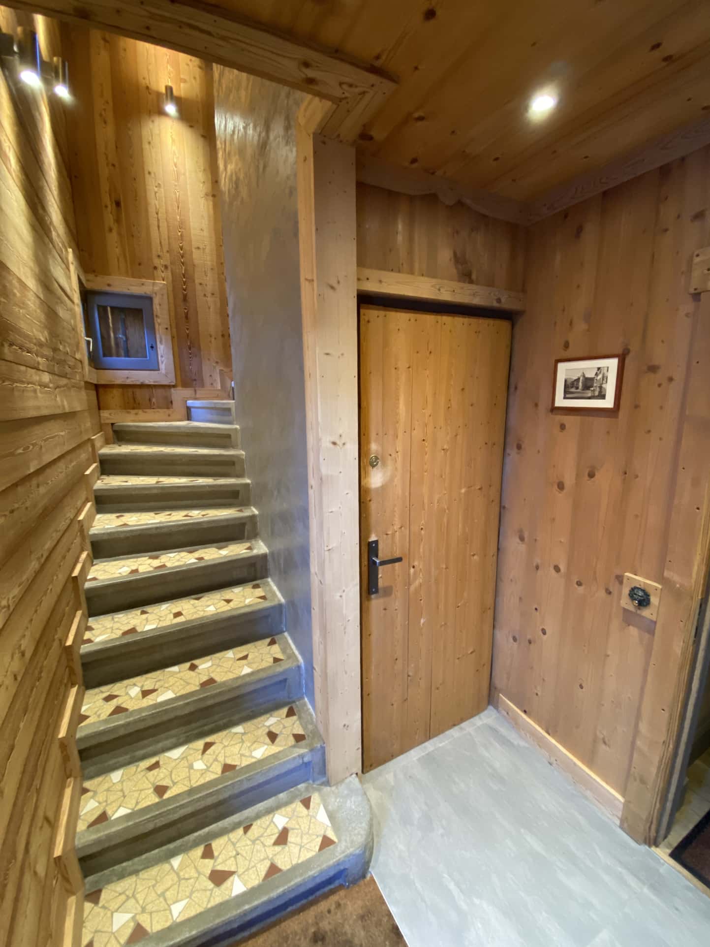 Entrance to a renovated apartment with wooden stairs and wooden door, chalet style.