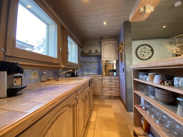 Kitchen in a renovated apartment with wooden furniture and colored tiles.