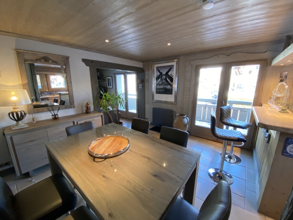 Interior of a renovated apartment with a dining table and a seating area in a chalet in Megève.