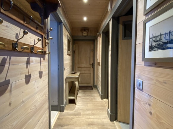 Hallway of a renovated apartment with wooden walls and modern lighting.