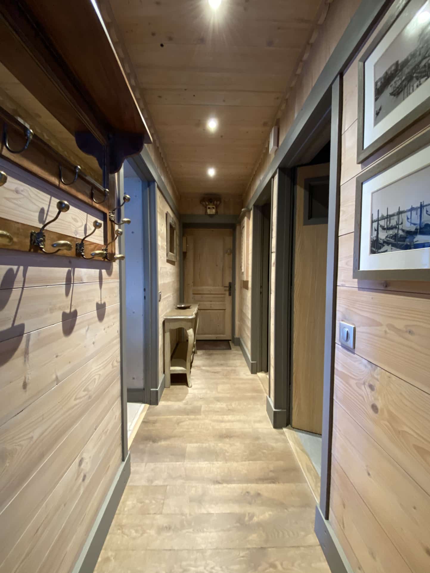 Hallway of a renovated apartment with wooden walls and modern lighting.