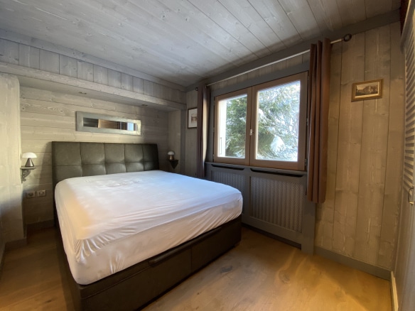 Room in a renovated apartment in Megève with a double bed and windows overlooking the outside.