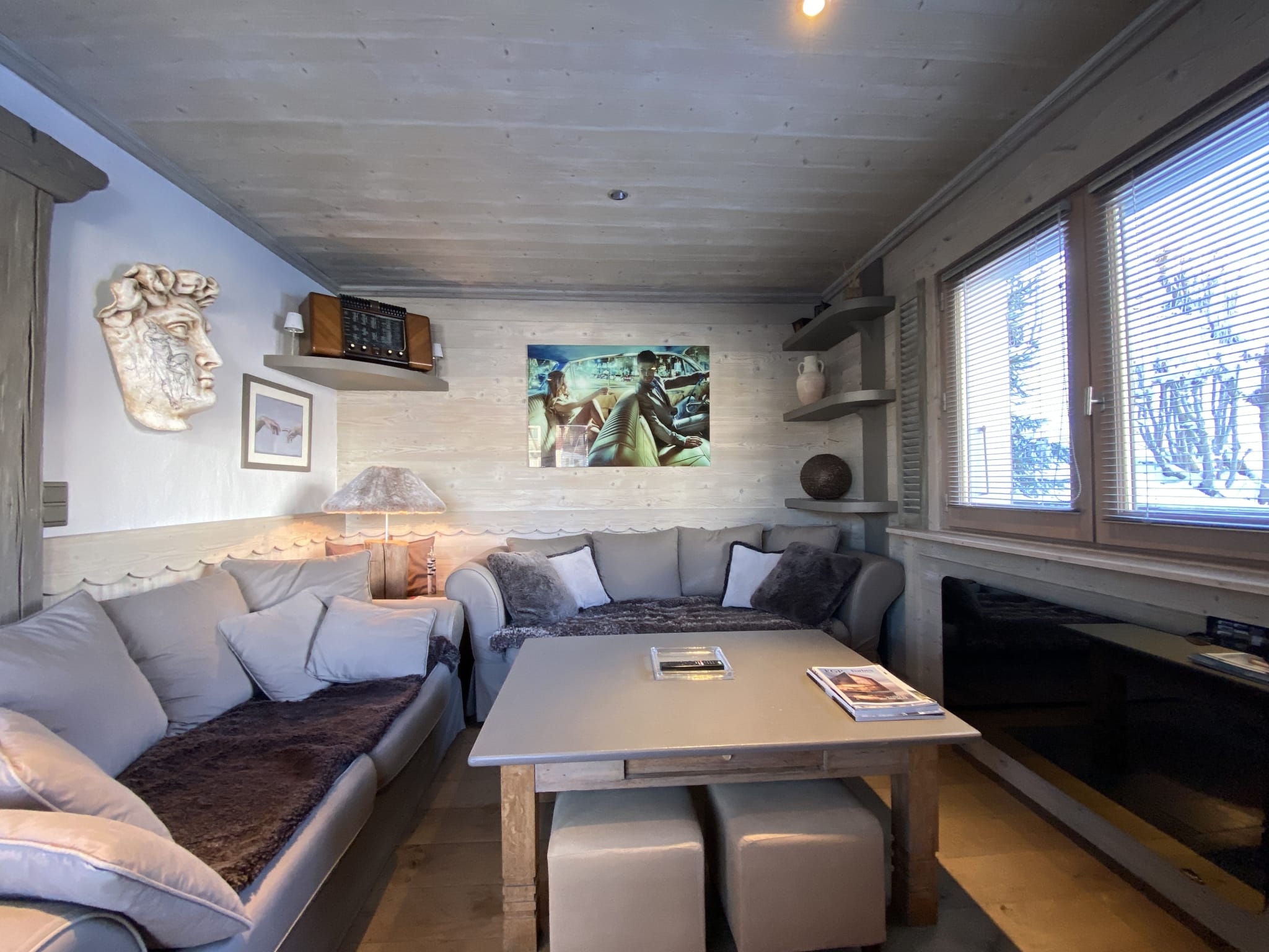 Cozy living room in a renovated apartment with sofa and coffee table, windows with a view of the snow.