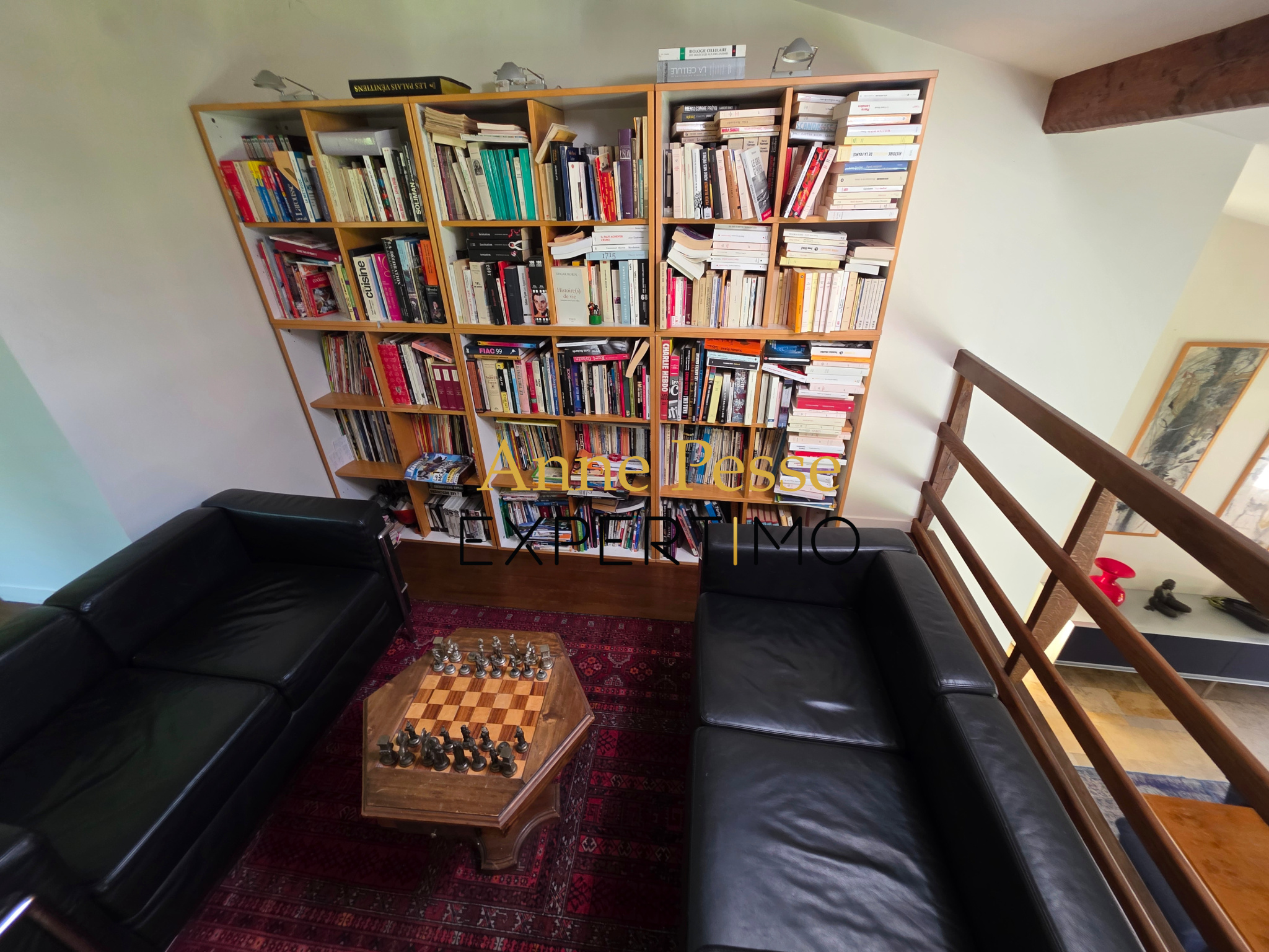 Intérieur d'une villa moderniste avec des étagères pleines de livres et un salon confortable.
